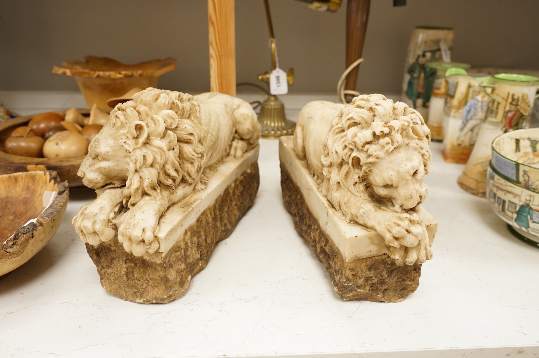 A pair of 20th century faux marble models of recumbent lions, 31cm